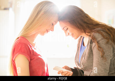 Teenage Girls texting with cell phone tête à tête de Banque D'Images