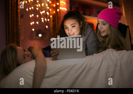 Teenage Girls using digital tablet on bed Banque D'Images