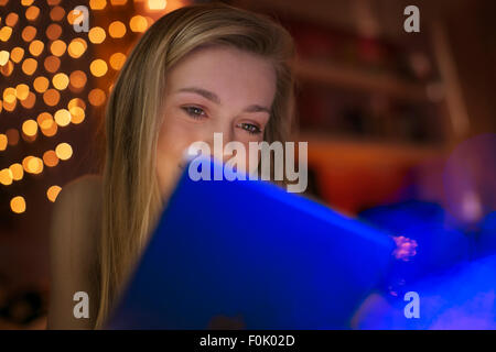 Teenage girl using digital tablet in dark room Banque D'Images