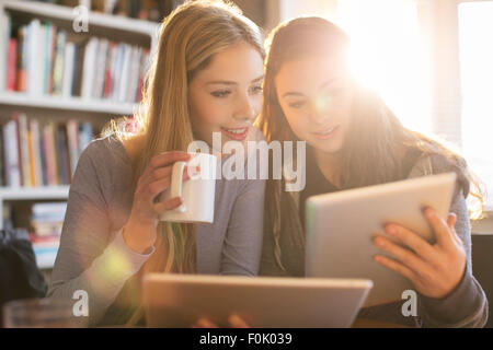 Les jeunes filles à boire du café et à l'aide de tablettes numériques Banque D'Images