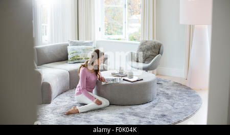 Woman Reading magazine sur le pouf dans la salle de séjour Banque D'Images