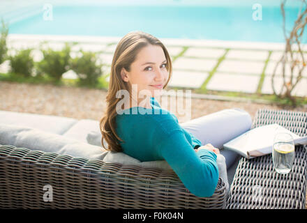 Portrait of smiling woman reading magazine à la piscine de luxe Banque D'Images