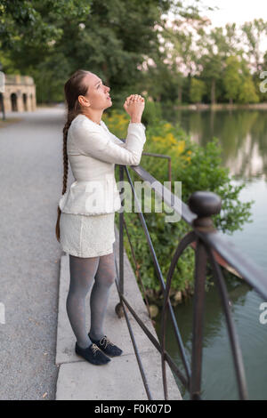 Jeune femme qui prie dans le port tout en regardant vers le ciel Banque D'Images