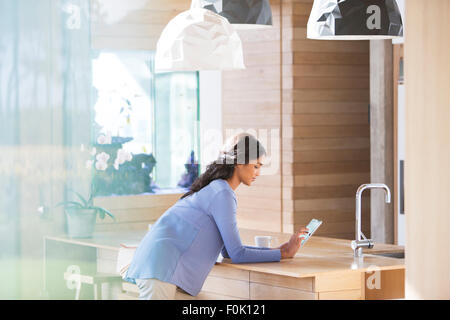 Woman using digital tablet in kitchen Banque D'Images