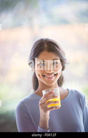 Portrait of smiling woman drinking orange juice Banque D'Images