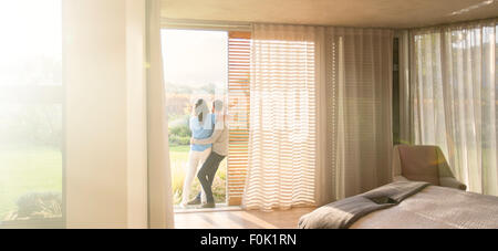 Couple hugging at porte patio dans la chambre Banque D'Images