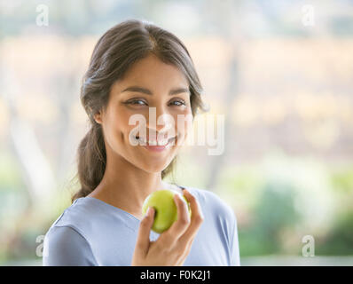 Close up portrait of smiling woman eating apple Banque D'Images