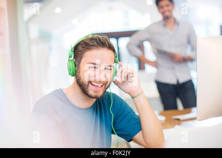 Creative Smiling woman listening to headphones in office Banque D'Images