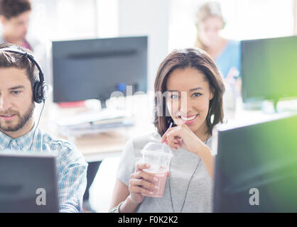 Portrait confident businesswoman drinking smoothie in office Banque D'Images