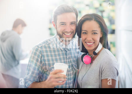 Smiling portrait des gens d'affaires créatifs avec des écouteurs et du café Banque D'Images