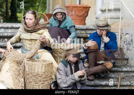 Famille de classe inférieure assis sur les marches d'un manoir dans l'ère victorienne Banque D'Images