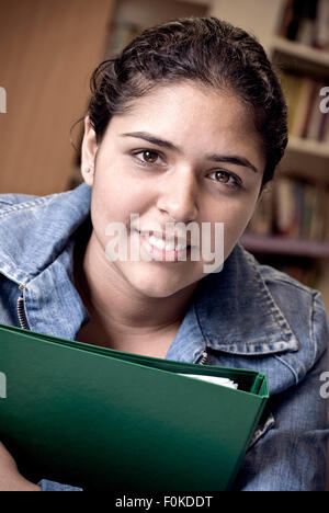 Portrait of smiling teenage girl confiant attrayant avec son dossier d'étude d'étudiant en bibliothèque de l'école Banque D'Images