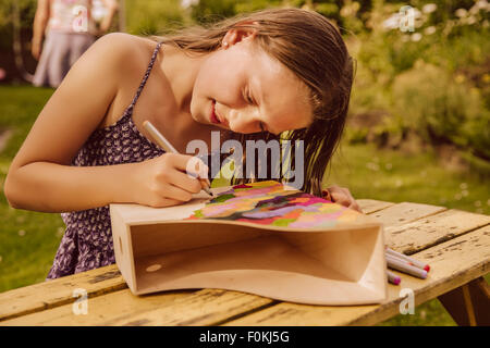 Girl dessin sur un magazine en bois fichier dans jardin Banque D'Images