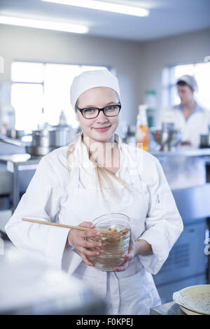 Portrait of teenage girl in kitchen cooking class holding bols à dessert Banque D'Images