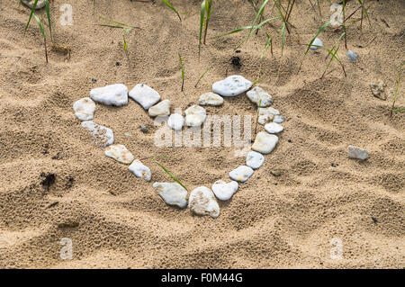 Le symbole en forme de coeur fait de petites pierres sur une plage sauvage Banque D'Images