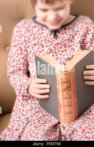 Petite fille dans un vieux livre de lecture. Image conceptuelle de l'intelligence et l'apprentissage de la lecture à un jeune âge. Banque D'Images