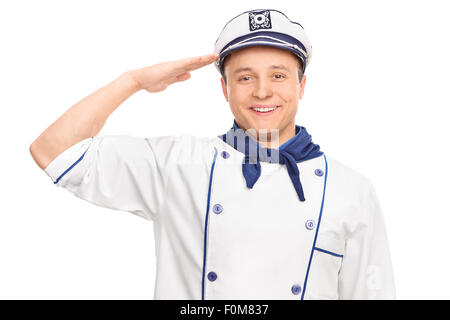 Cheerful young male sailor saluting vers la caméra et souriant isolé sur fond blanc Banque D'Images