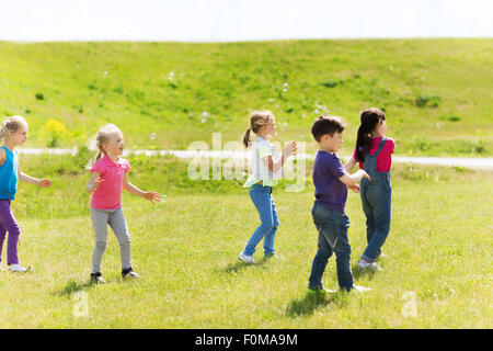 Groupe d'enfants attraper des bulles de savon en plein air Banque D'Images