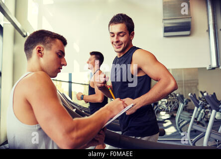 Les hommes exerçant sur tapis roulant dans une salle de sport Banque D'Images