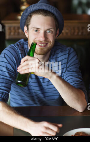 Happy young man drinking beer au bar ou au pub Banque D'Images