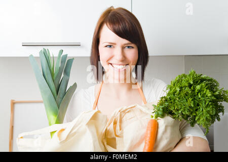Jeune femme dans la cuisine avec les sacs plein de légumes Banque D'Images