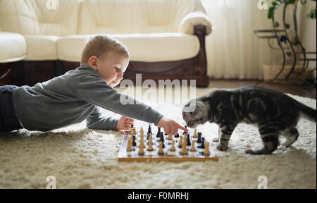 Petit garçon joue aux échecs lying on floor Banque D'Images