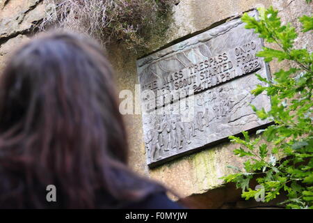 Une femelle walker inspecte la plaque dans la carrière de pont sous gaine qui commémore le sacrifice de masse de Kinder Scout, Derbyshire, Royaume-Uni Banque D'Images