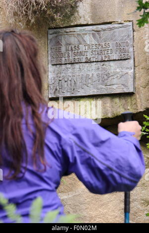 Une femelle walker inspecte la plaque dans la carrière de pont sous gaine qui commémore le sacrifice de masse de Kinder Scout, Derbyshire, Royaume-Uni Banque D'Images