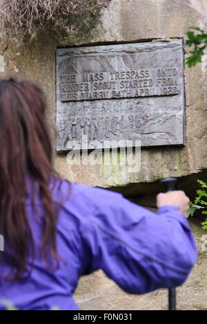 Une femelle walker inspecte la plaque dans la carrière de pont sous gaine qui commémore le sacrifice de masse de Kinder Scout, Derbyshire, Royaume-Uni Banque D'Images