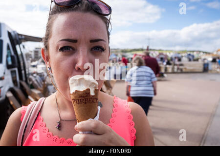 Jeune femme mangeant une glace à la station Banque D'Images