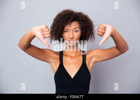 Portrait d'une jeune femme africaine showing thumb sur fond gris Banque D'Images