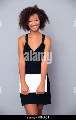 Portrait d'une femme heureuse debout avec coffre sur fond gris et looking at camera Banque D'Images
