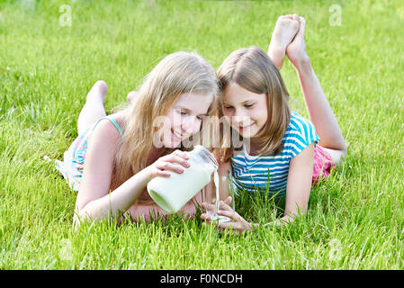 Deux jeunes filles se trouvant dans la ville ensoleillée de prairie avec une cruche de lait Banque D'Images