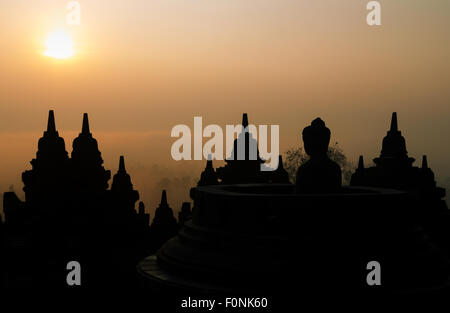 Silhouettes d'une statue de Bouddha au site du patrimoine mondial de l'Unesco le Borobudur temple à l'aube sur l'île de Java, en Indonésie, en Asie. Banque D'Images