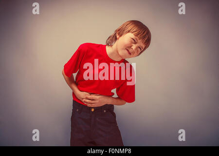 Adolescent, garçon de douze ans en chemise rouge douleur abdominale, gastriti Banque D'Images