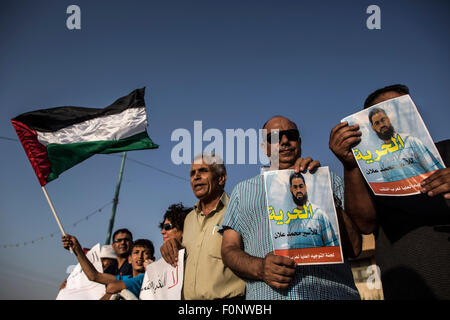 (150819) -- RAHAT (Israël), le 19 août 2015 (Xinhua) -- des manifestants arabes, d'un drapeau palestinien et tenir les affiches de Mohammed Allan, un prisonnier palestinien qui est sur une grève de la faim à long terme, au cours d'un rassemblement afin de demander sa libération en Rahat, dans le sud d'Israël, le 18 août, 2015. Prisonnier palestinien qui a glissé dans le coma la semaine dernière, après deux mois de grève de la faim a réveillé le mardi et a promis de reprendre le jeûne si Israël n'a pas régler son cas dans les 24 heures. Le Club des prisonniers palestiniens a déclaré dans un communiqué que Mohammed Allan a déclaré devant ses médecins que s'il n'y a pas de solution Banque D'Images