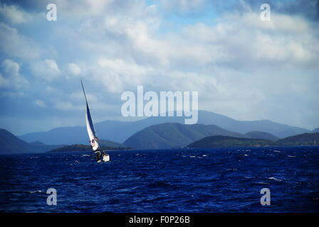 Bleu mer sur un nuage ensoleillée journée pleine de voiles d'un bateau entre les îles de St John, US Virgin Islands. Banque D'Images