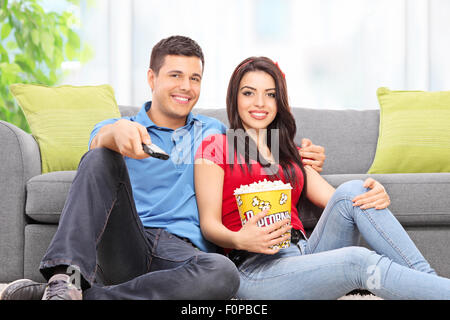 Jeune couple en regardant la télé assis sur le plancher à la maison Banque D'Images