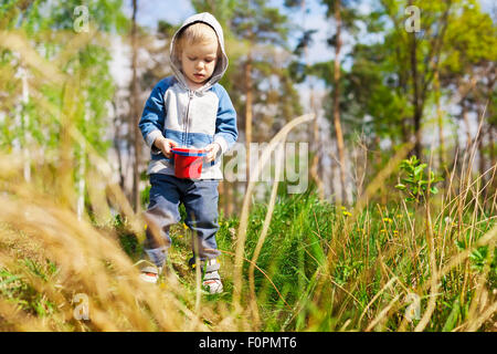 Little boy playing with toy bucket en plein air Banque D'Images