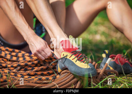 Close up rock climber mise sur chaussures d'escalade tout en étant assis sur l'herbe Banque D'Images