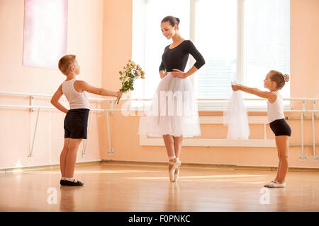 En danse classique Catégorie : jeune garçon et fille donnant des fleurs et voile à étudiant plus âgé alors qu'elle danse en pointe Banque D'Images