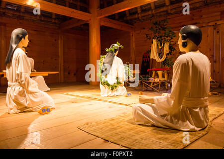 Le Japon, le parc historique Yoshinogari. Intérieur du Palace, de l'intérieur de la salle de l'assemblée, les femmes à genoux avec des mannequins au cérémonie rituelle. Banque D'Images