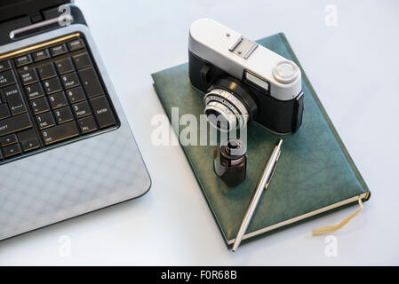 35mm vintage photocamera sur journal intime avec le cinéma, l'ordinateur portable et stylo Banque D'Images