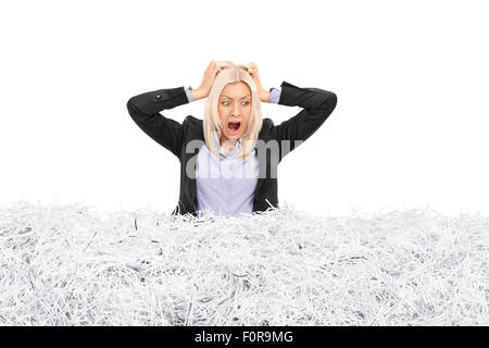 Portrait d'une jeune femme d'furieux coincé dans une pile de papier déchiqueté isolé sur fond blanc Banque D'Images