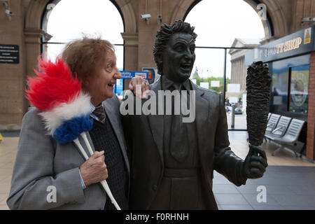 Funny-man Ken Dodd est à côté d'une statue de lui-même dans le centre de Liverpool Lime Street Station. Banque D'Images