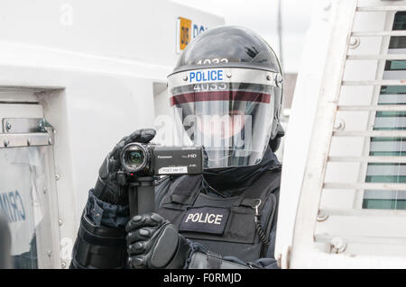 Un agent de police PSNI habillés en uniforme antiémeute utilise une caméra vidéo afin de recueillir des éléments de preuve lors d'un désordre public riot Banque D'Images