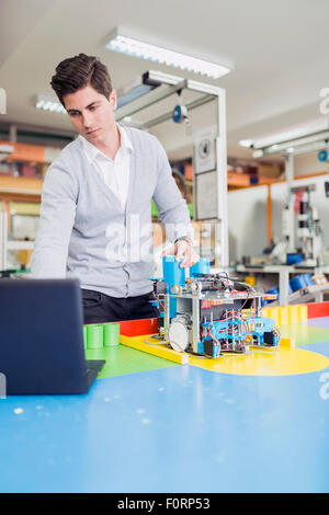 Ingénieur électrique mâle de la programmation d'un robot à la classe de robotique Banque D'Images