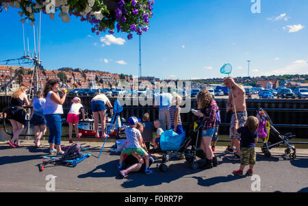 Une foule de vacanciers dans le soleil d'été sur le quai de pêche dans le port de Whitby Banque D'Images