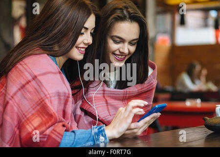 Deux fille assise à écouter de la musique avec un smartphone Banque D'Images