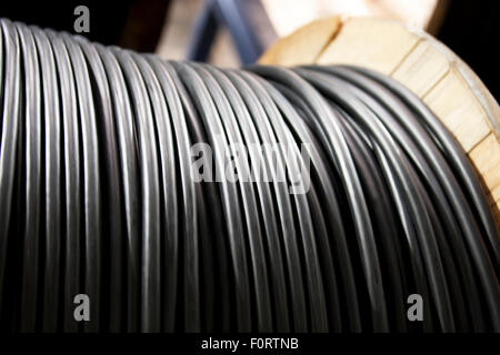 Câble électrique noir sur un rouleau en bois Banque D'Images